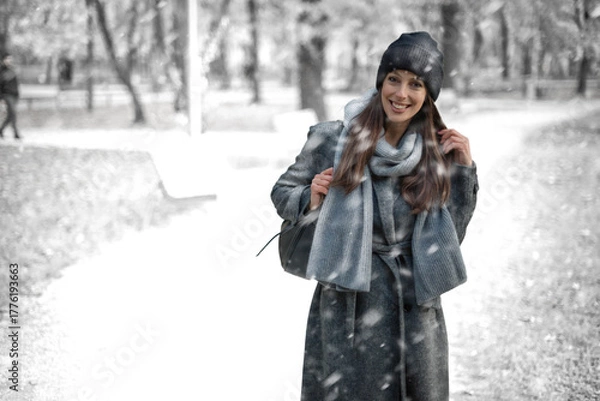 Obraz Cheerful smiling woman standing in the snowfall at the park
