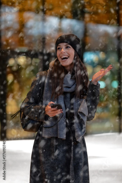 Obraz Happy female standing in the snowfall at the city