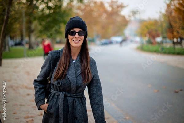 Obraz Smiling middle-aged woman wearing scarf and beanie in a park during the autumn season