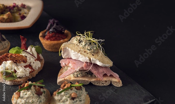 Fototapeta Assorted gourmet canapes on slate board close-up