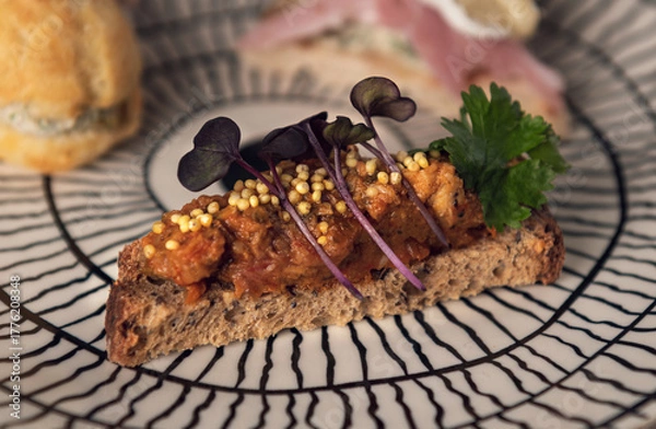 Fototapeta Gourmet toast with vegetable spread and microgreens on patterned plate
