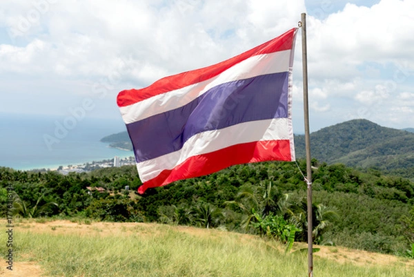 Fototapeta The Thai flag flutters against a forest backdrop. A symbol of Thai identity, culture, and patriotism