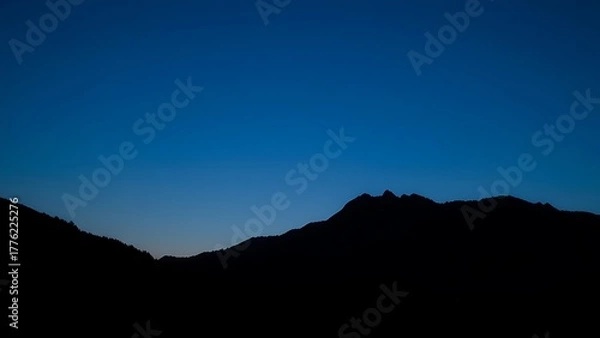 Obraz A majestic mountain silhouette against a twilight sky, radiating calm and natural beauty.