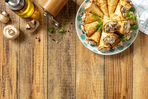 Fototapeta Crispy lavash rolls with mushroom filling, cheese and herbs on a rustic wooden table. Top view.