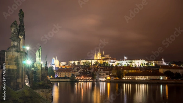 Fototapeta Prague Castle and Charles Bridge in Prague, Czech Republic. Light of lanterns reflected in the river Vltava. Sculptures on the bridge