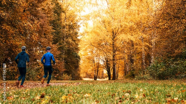 Fototapeta Running athletes in the park on a run in the early morning. Several children are running in the woods doing sports. Healthy lifestyle.