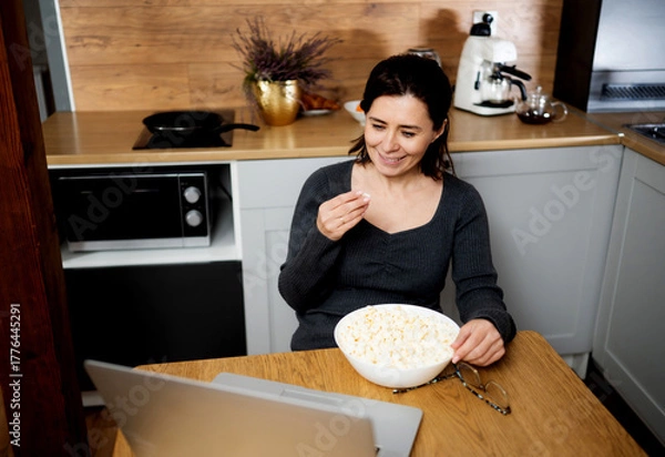 Obraz Smiling Girl Watching A Video On A Laptop Screen And Eating Popcorn