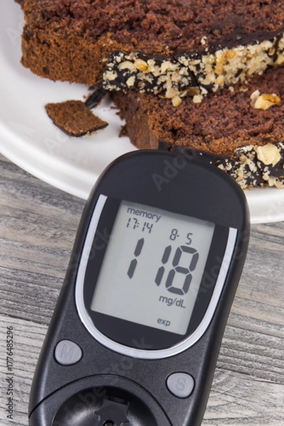 Fototapeta Glucose meter with result sugar level, sweet chocolate cake. Measuring and checking sugar level during diabetes