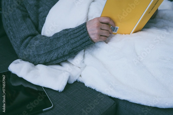 Fototapeta Paper books vs ebooks. Woman reads a physical book, tablet sits unused. Pleasure of traditional reading