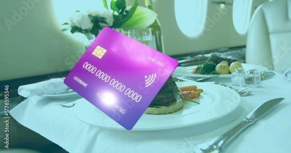 Fototapeta Floating purple-blue bank card displaying EMV chip above jet tray table with steak and vegetables