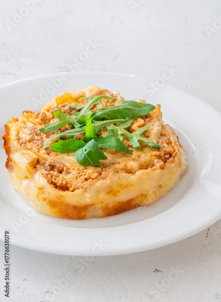 Obraz Circular lasagna presentation topped with fresh arugula served on elegant white plate
