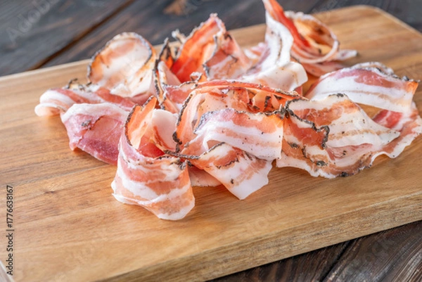 Fototapeta Rustic presentation of sliced Italian pancetta arranged neatly on wooden cutting board