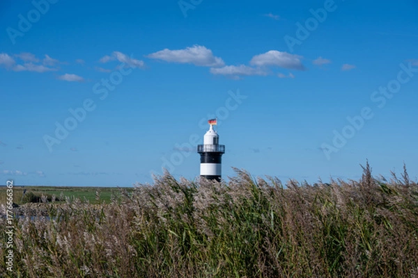 Fototapeta Small lighthouse in Wremen on the North Sea coast, with grasses in the foreground