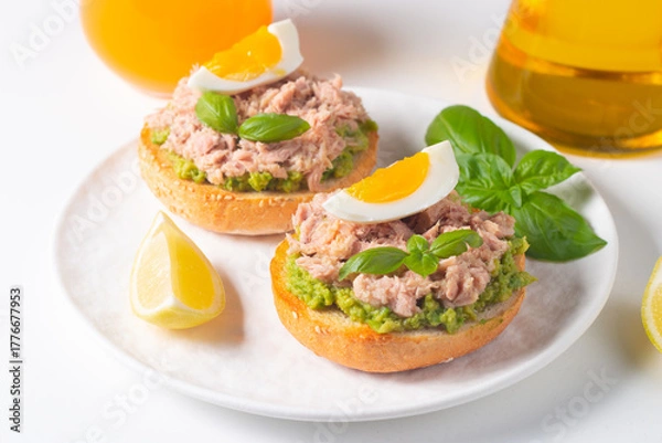 Fototapeta Two delicious tuna open sandwiches with avocado and boiled eggs. Tuna toast.