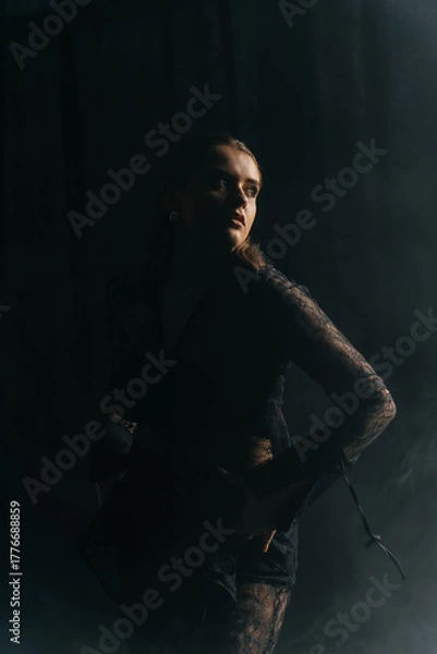 Fototapeta A mysterious woman stands in silhouette against a bright window, surrounded by dramatic smoke and shadows