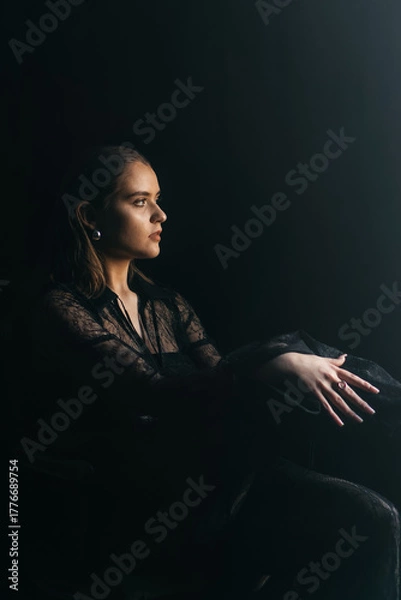 Fototapeta A mysterious woman stands in silhouette against a bright window, surrounded by dramatic smoke and shadows
