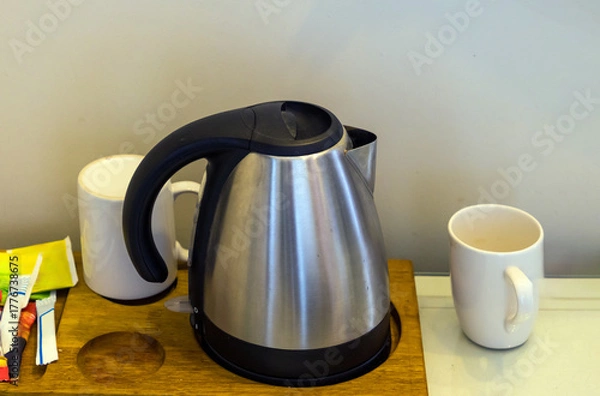 Fototapeta Tea kettle with ceramic cup on table interior