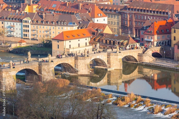 Fototapeta Historic Old Main Bridge with statues over Main River in Wurzburg, Germany with people walking across on sunny day