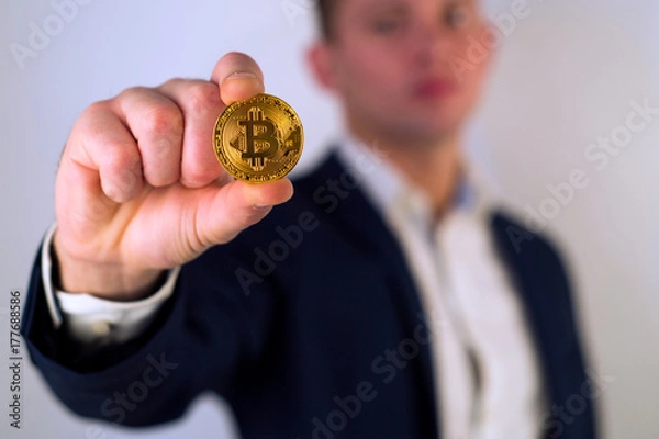 Fototapeta Golden Bitcoin in a man hand, Digitall symbol of a new virtual currency