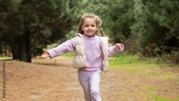 Fototapeta Joyful child running in nature's forest pathway. Nature