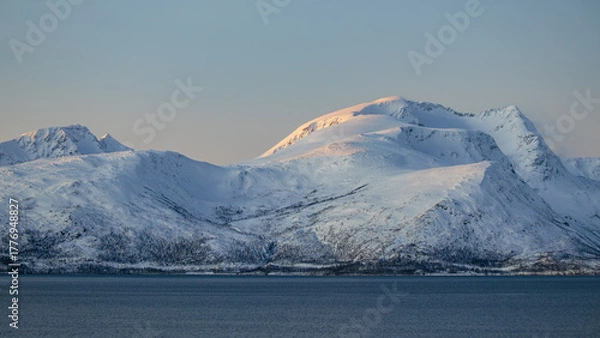 Fototapeta Golden sunlight on snowy mountains above Arctic fjord in Tromsø, Norway