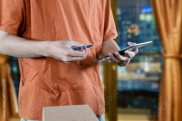 Fototapeta Close-up of an online shopper holding a credit card and digital tablet to make a purchase.