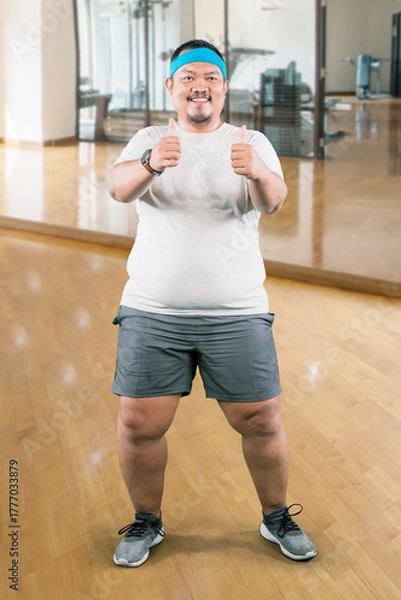 Fototapeta Full Body Portrait of a Happy Overweight Man Giving Double Thumbs Up at the Gym
