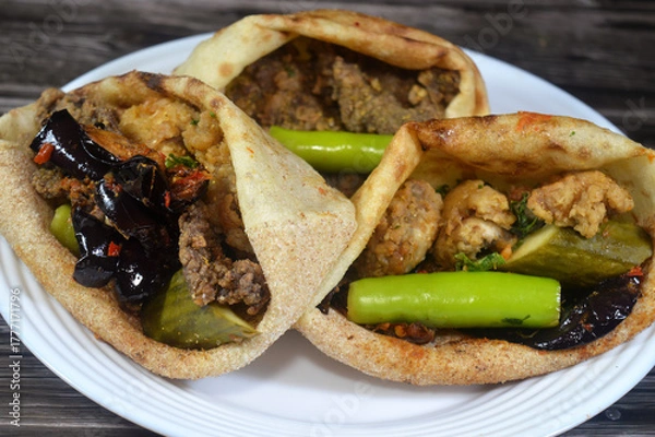 Obraz A plate of Fried beef brain, beef liver slices deep fried in oil and served with parsley in a traditional Egyptian flat bread with wheat bran and flour, regular Aish Baladi or Egypt bread