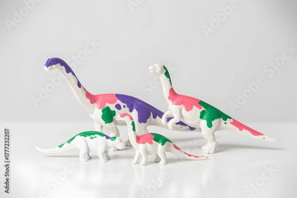 Obraz Colorful dinosaur toys standing together on a white background