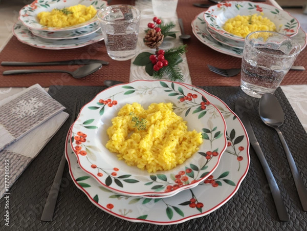 Obraz Table setting with bright tableware, berries, and twigs. Saffron risotto on plate. Traditional Italian food. Aesthetics and lifestyle. Interior design. 