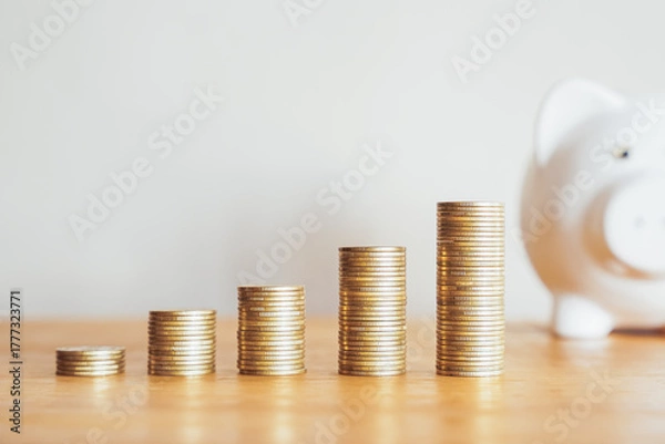 Fototapeta Piggy bank and a growing stack of gold coins symbolize savings, investment, and financial growth in banking and business