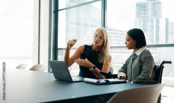 Obraz Two businesswomen discussing plans in a modern office setting