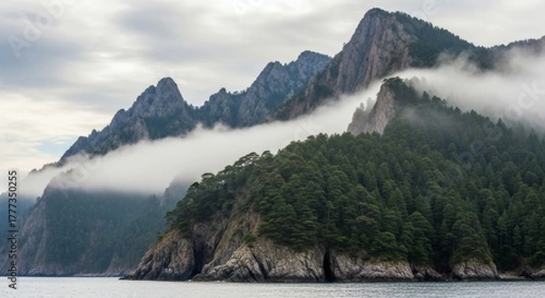 Fototapeta Majestic peaks and lush green forests emerge from the water, shrouded in ethereal fog