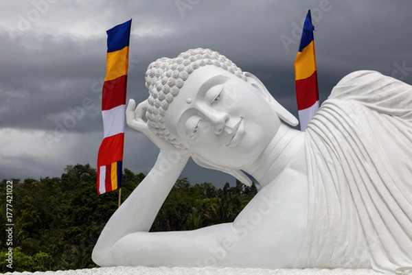 Fototapeta Closeup of the giant sleeping Buddha statue at the temple of Vihara Dharma Giri in northern Bali, Indonesia. Flags and cloudy sky in the background.
