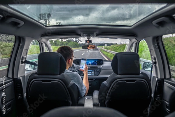 Fototapeta Driver using smartphone on rainy highway. Navigation on the move.