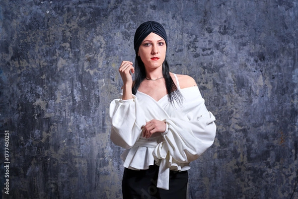 Obraz In a dark room stands a beautiful girl with long hair, dressed in a black leather skirt and a white blouse. Her outfit is designed in a business style. This is the image of a business woman.