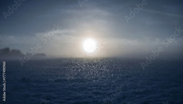 Obraz Sunset over a calm sea with foggy horizon and blue sky