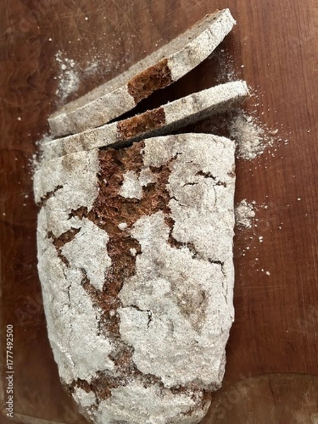 Obraz freshly baked sourdough bread sliced on wooden cutting board, directly above