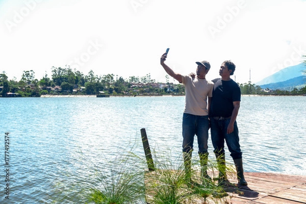 Fototapeta Two Friends Capturing Memories With Lakeside Selfie on Summer Day