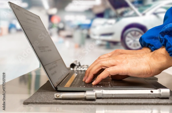 Fototapeta Close-up of hands of manager at the auto repair shop planning operations using laptop