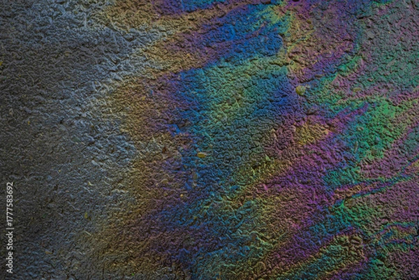 Fototapeta Colorful oil spill on wet asphalt creates vibrant rainbow texture with shimmering light reflections. Concept of environmental pollution and abstract colorful background