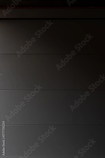 Fototapeta Porte de garage grise anthracite installée par un professionnel, encadrée par un mur en pierre beige et un sol en macadam, entre modernité et authenticité.