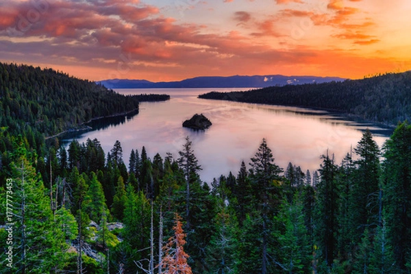 Fototapeta Sunrise over Emerald Bay State Park at Lake Tahoe California USA with colorful pink and orange sky reflecting in calm water surrounded by pine forest and mountains in scenic Sierra Nevada landscape