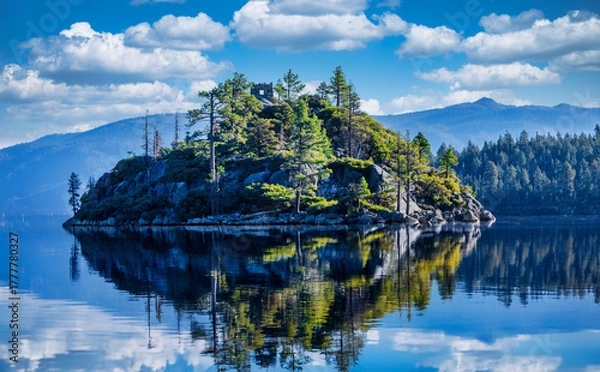 Fototapeta Fannette Island in Emerald Bay State Park at Lake Tahoe California USA with stone tea house ruins surrounded by pine trees reflected in calm blue water and Sierra Nevada mountains on sunny summer day