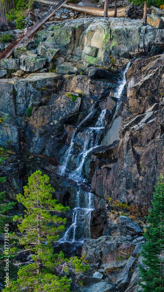 Fototapeta Scenic waterfall cascading down rugged granite cliffs surrounded by pine trees in Emerald Bay State Park at Lake Tahoe California USA, captured during summer in clear daylight from mountain trail