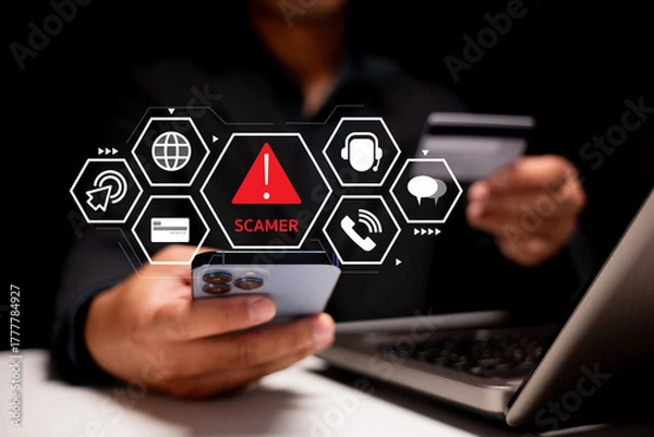 Fototapeta A person holds a smartphone displaying a warning about scammers, with digital icons representing online threats and security.