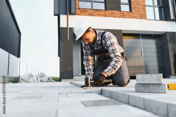 Obraz Construction worker paving driveway with concrete blocks