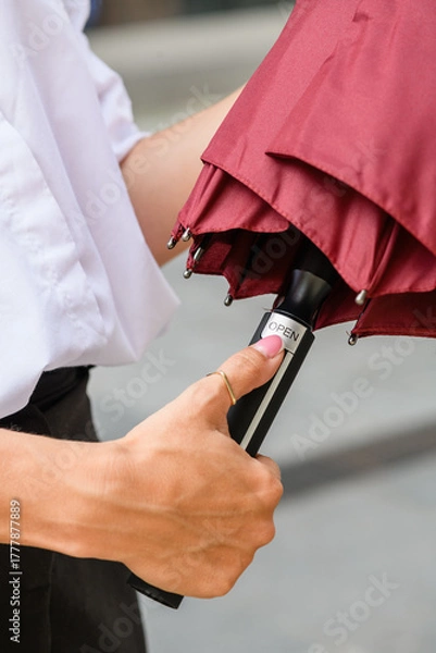 Obraz Woman pressing button to open red umbrella outdoors.