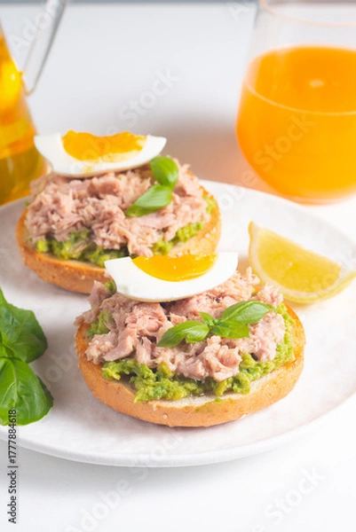 Fototapeta Two delicious tuna open sandwiches with avocado and boiled eggs. Tuna toast.