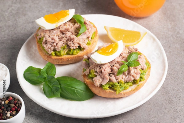 Fototapeta Two delicious tuna open sandwiches with avocado and boiled eggs. Tuna toast.